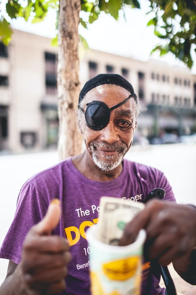 Homeless man happy while holding a cup with money